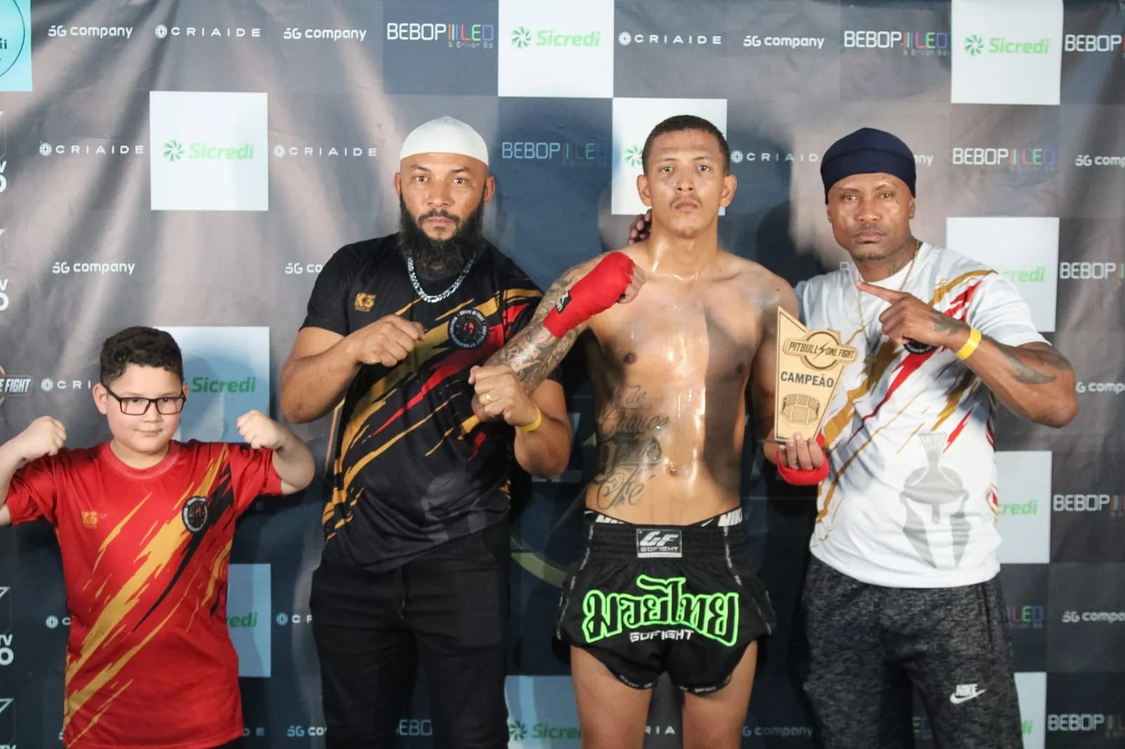 Atleta campeão com troféu de ouro ao lado do Prof. Nélsinho e equipe NT Fight